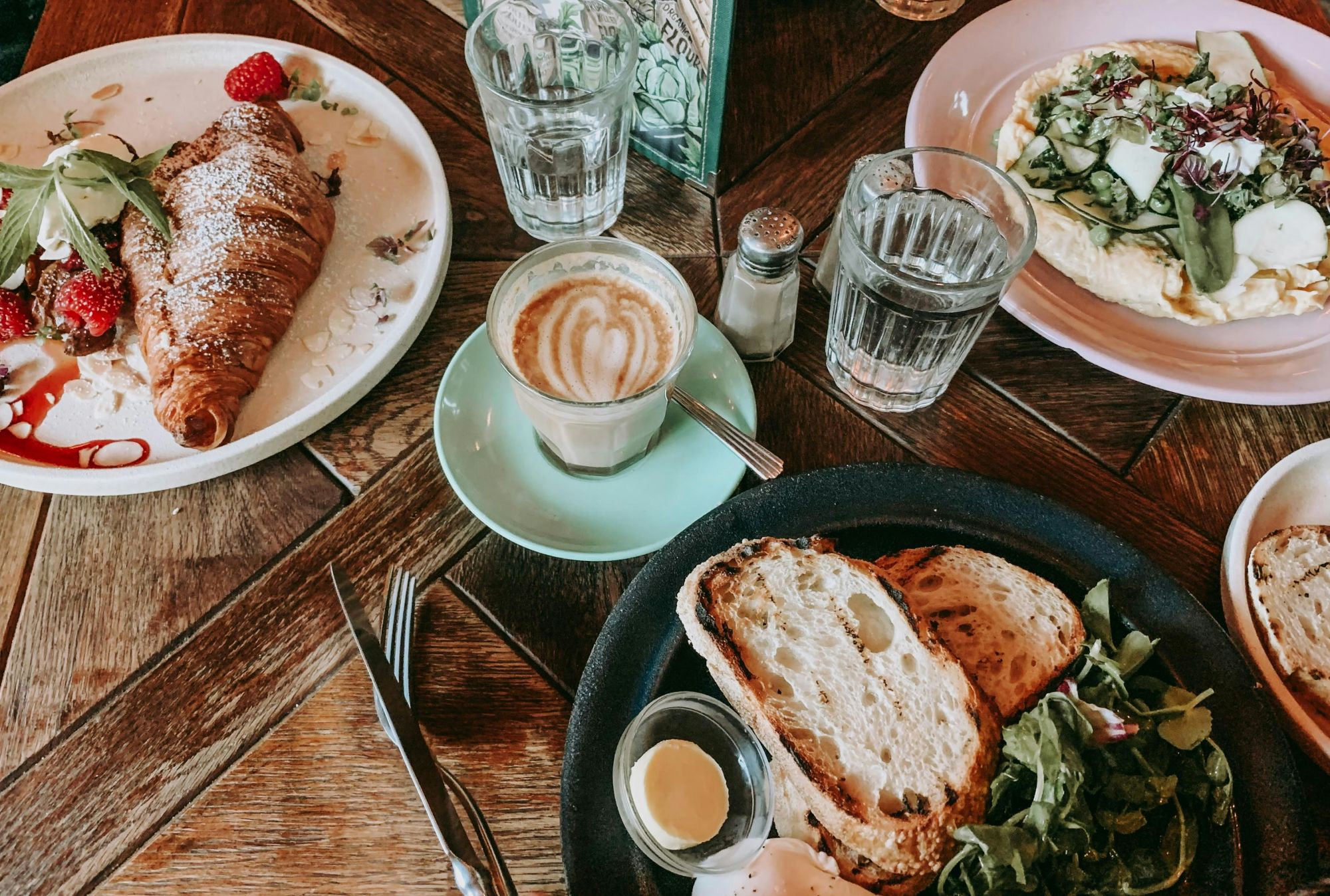 A table of brunch items, including coffee, croissants, scrambled egg, and toast.