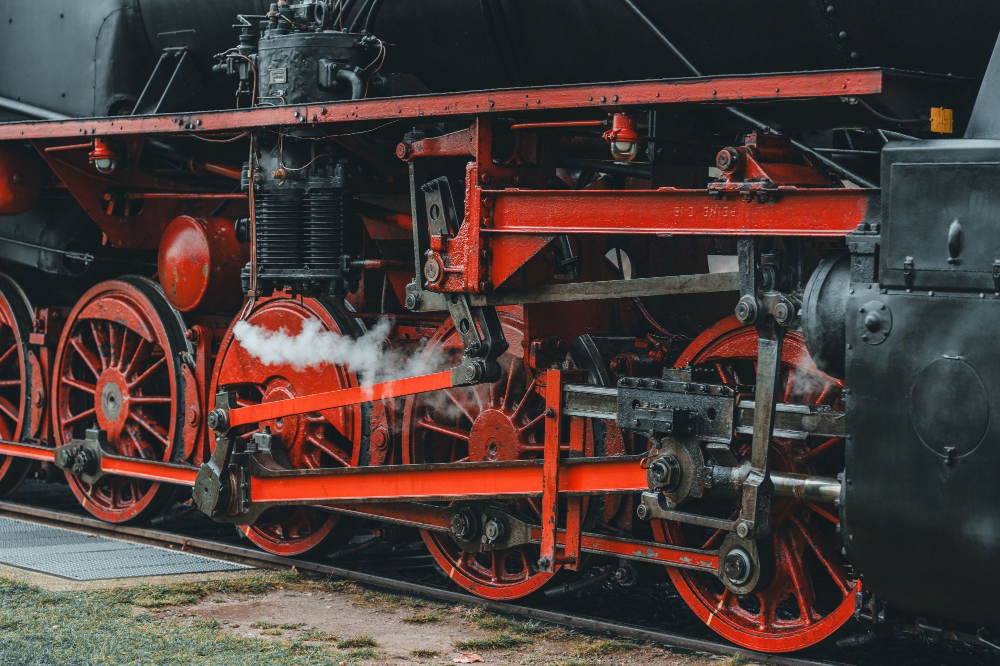 The wheels of a red and black steam engine.