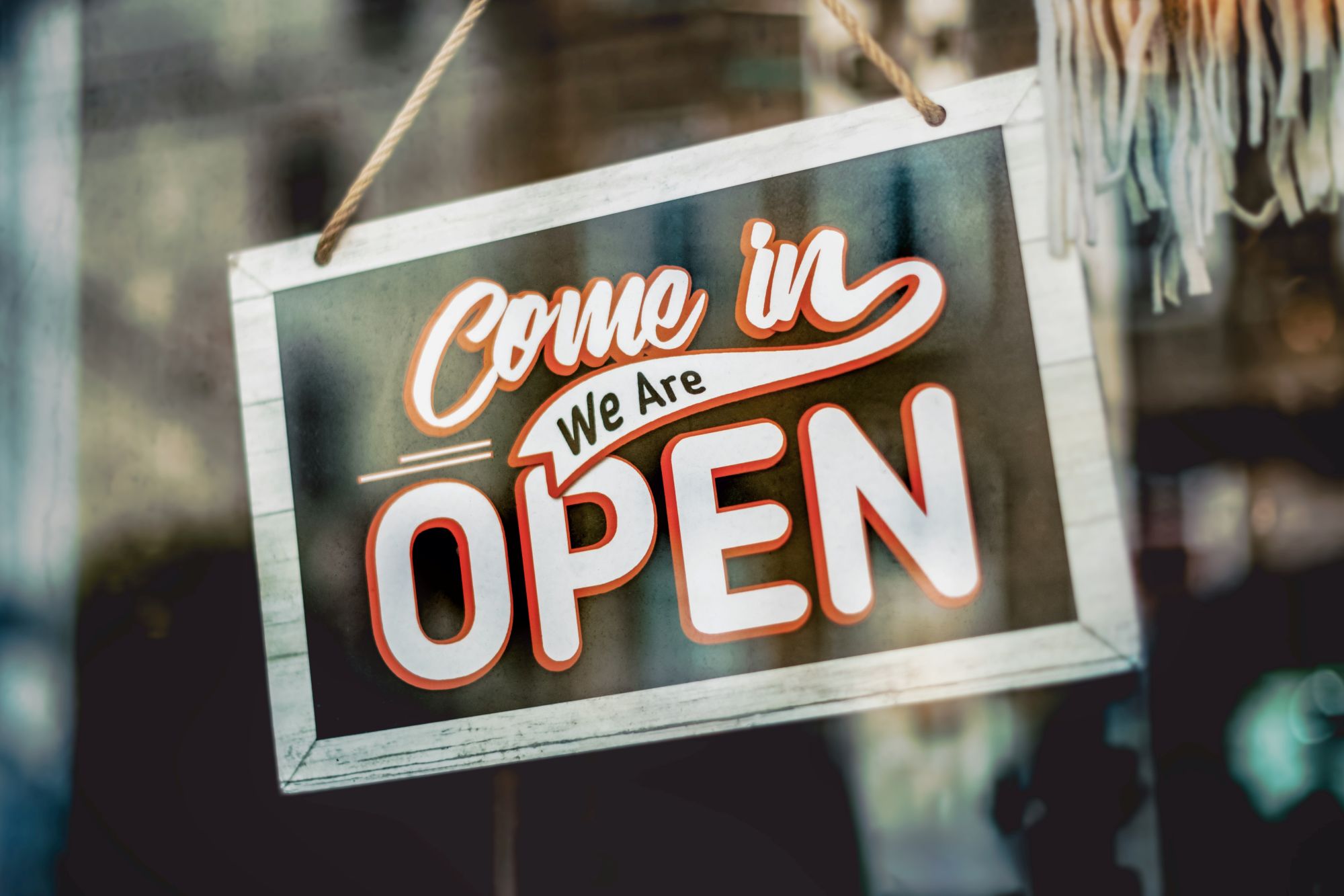  A hanging door sign saying ‘Come in we are open’
