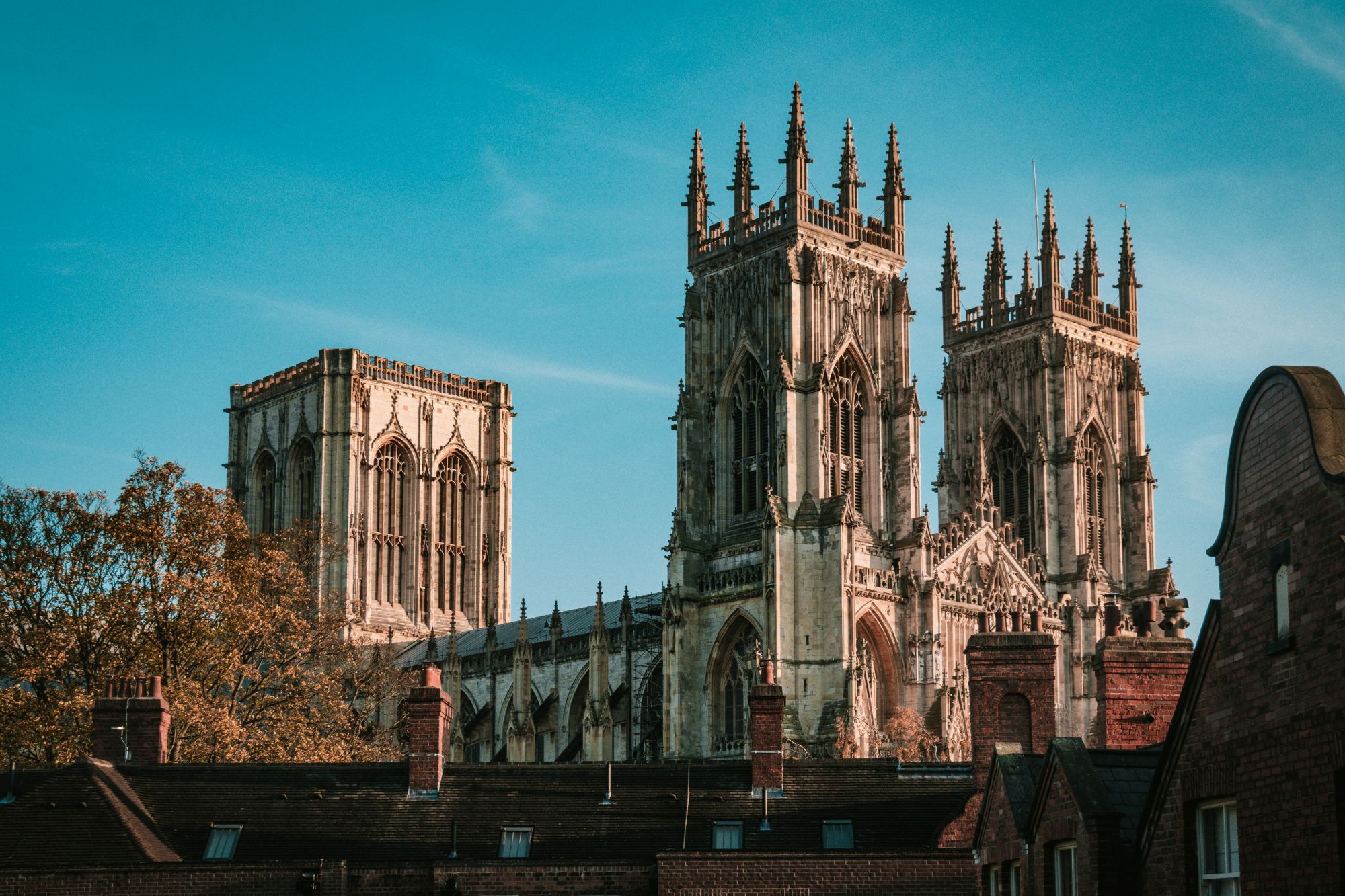 York Minster illuminated by sunlight above historic brick rooftops.