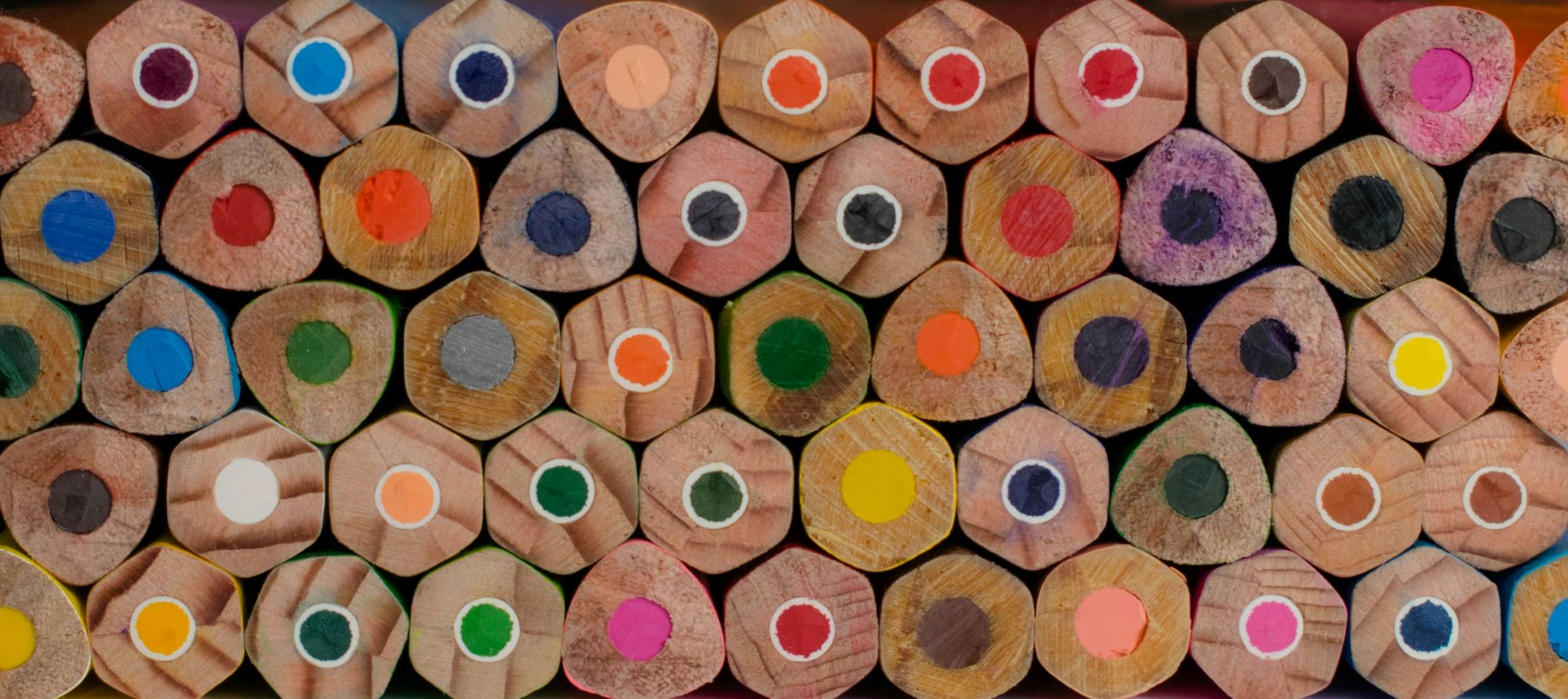 A close-up photograph of numerous hexagonal wooden coloured pencils.