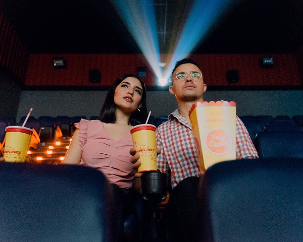 A couple watching a film with drinks and popcorn