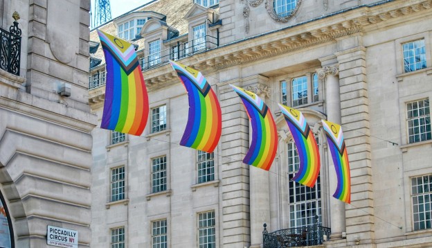 Progress Pride flags hanging along a city street.