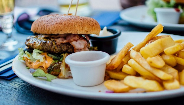 A bacon burger with chips.