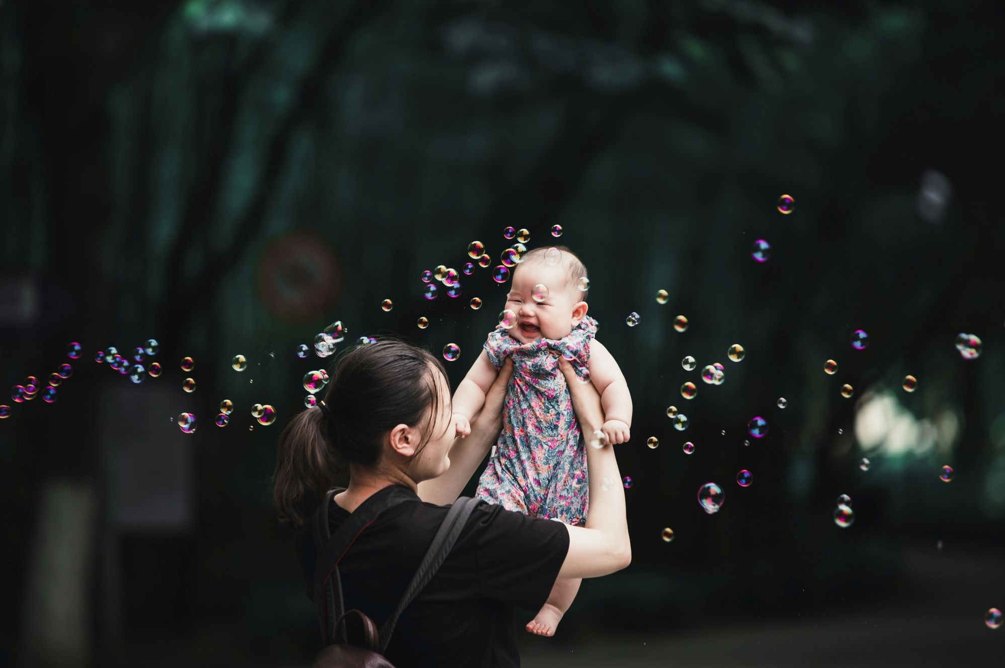  A mother holding her laughing baby, surrounded by bubbles.