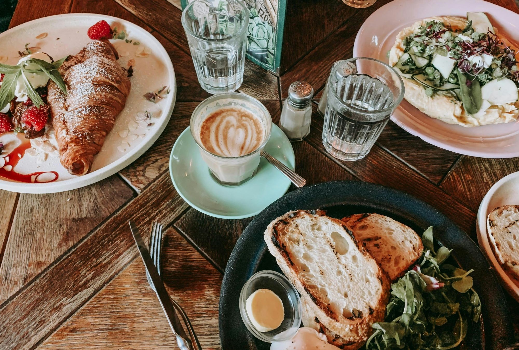 A table of brunch items, including coffee, croissants, scrambled egg, and toast.