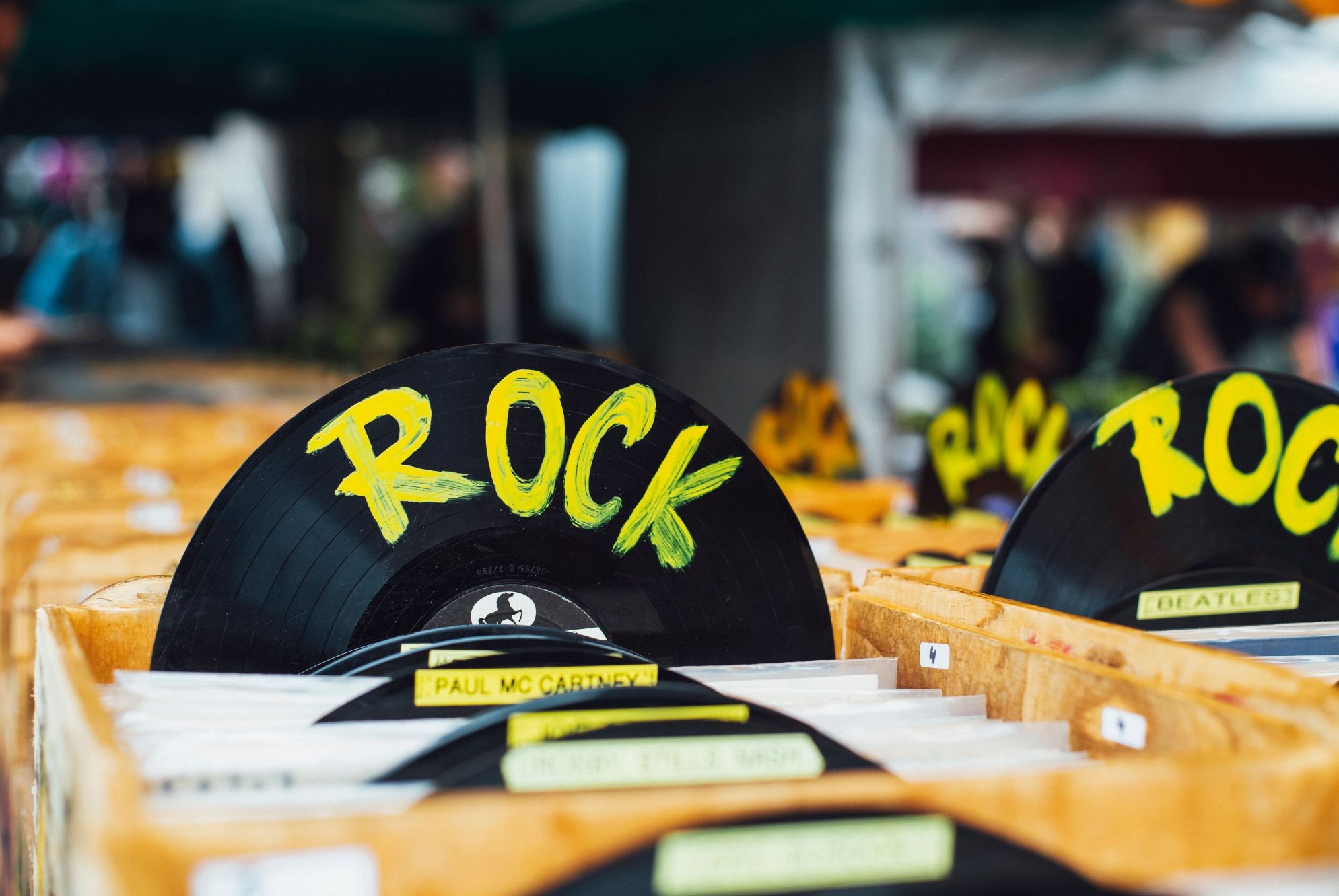 Wooden crates filled with vinyl records, featuring a large record used as a category divider with the word ‘ROCK’ painted in yellow.