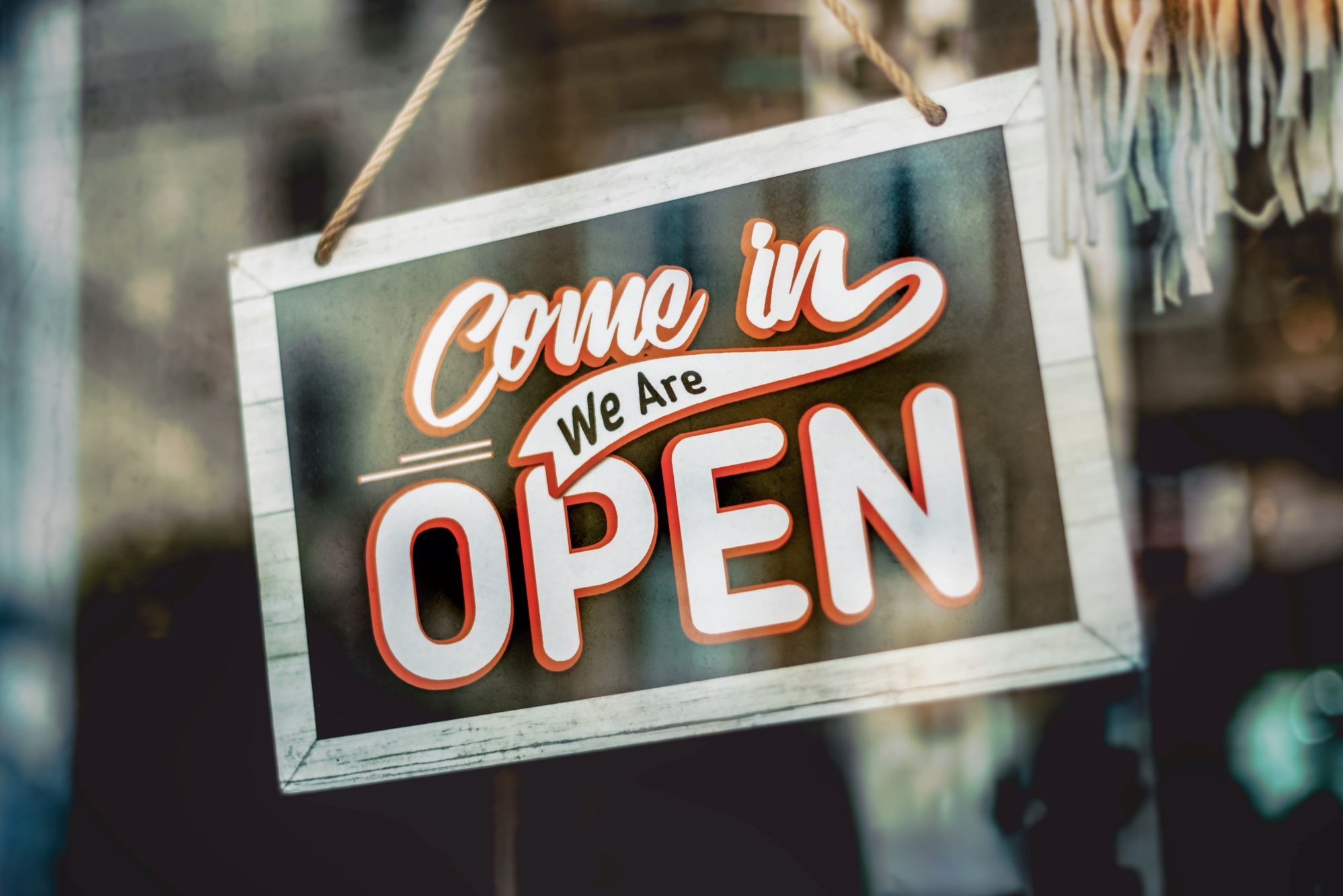  A hanging door sign saying ‘Come in we are open’