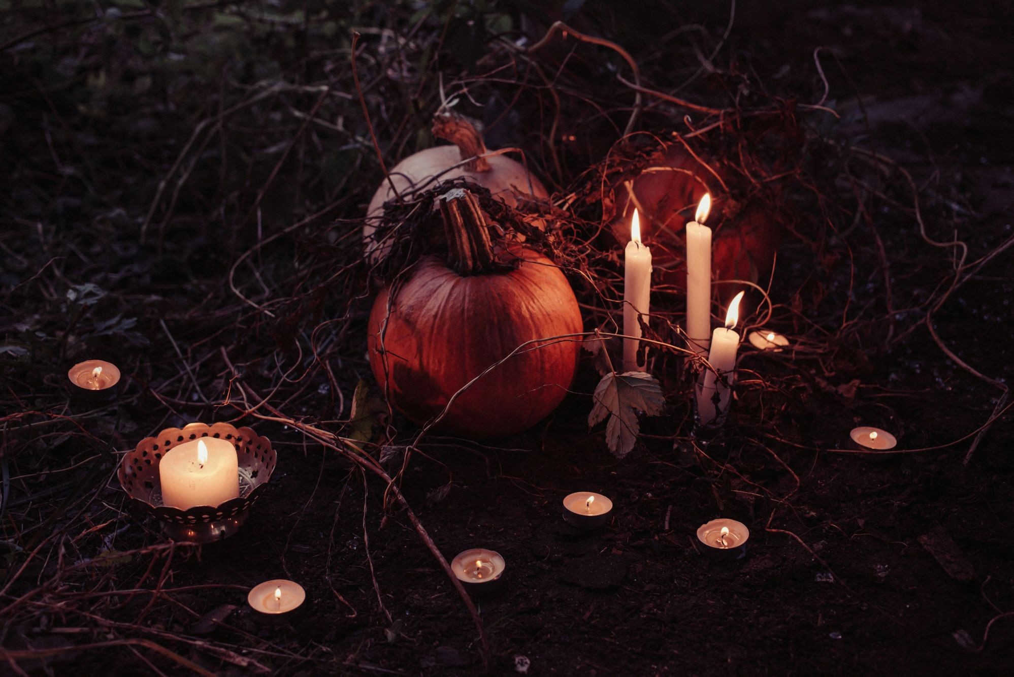 Pumpkins with a display of candles set out around them to create a spooky atmosphere during the season of Halloween.
