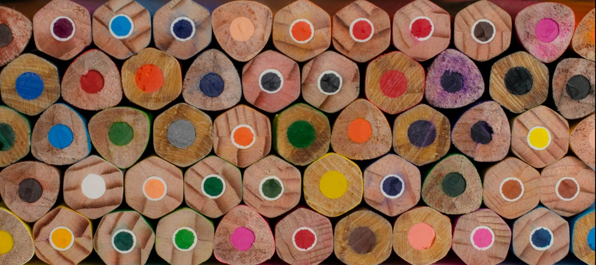 A close-up photograph of numerous hexagonal wooden coloured pencils.