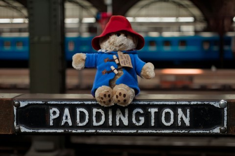 A toy Paddington Bear sitting on a small iron sign that says ‘PADDINGTON’