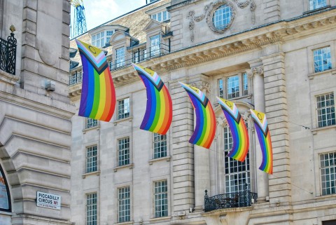 Progress Pride flags hanging along a city street.