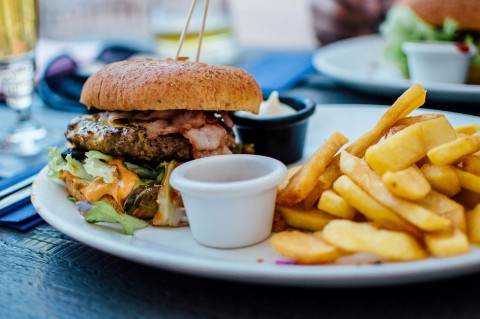 A bacon burger with chips.