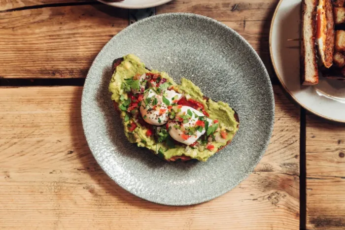Avocado toast with poached eggs on a grey plate at Saint Kitchen.