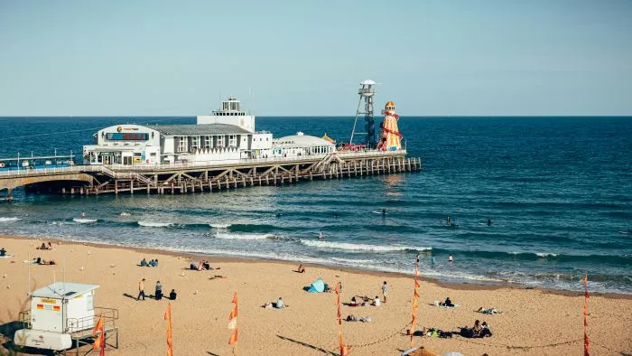 Bournemouth Pier on a sunny day surrounded by people enjoying a beach day.