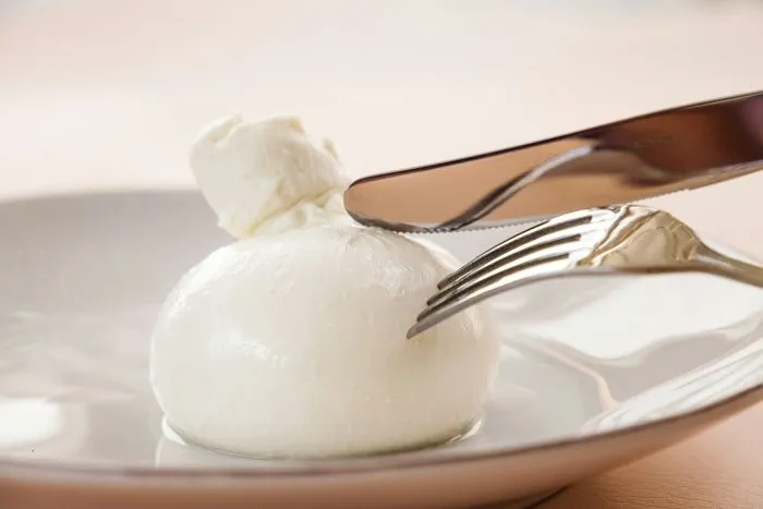 A knife and fork about to cut into a burrata.