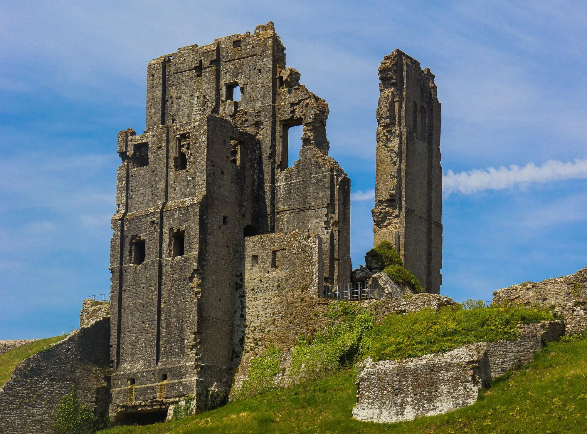 Historic stone ruins of Corfe Castle atop a lush green hill in Dorset.