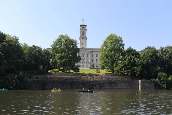 The Trent Building with its clock tower at the University of Nottingham, set behind a lake with small boats.