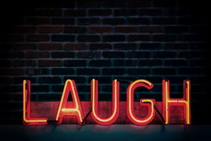 Alt: A neon red sign reading ‘LAUGH’. 