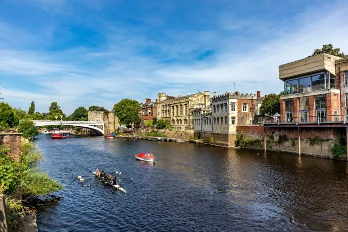 A scenic view of a wide river with a rowing crew and small boats.