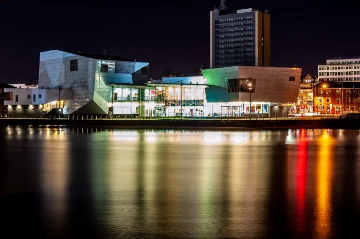 The Riverfront Theatre in Newport reflecting against the river at night.