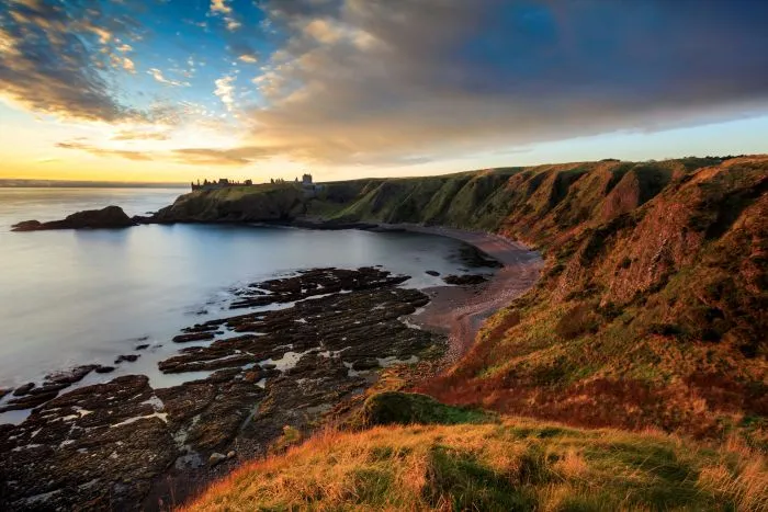 A distant view of Dunnottar Castle at sunrise.