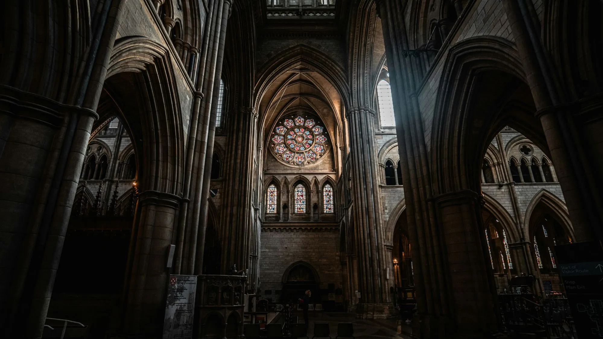 Truro Cathedral's Gothic stone arches framing a circular stained-glass rose window.
