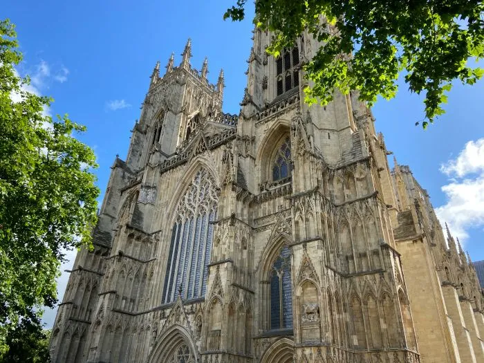 York Minster on a sunny day surrounded by green leaves.